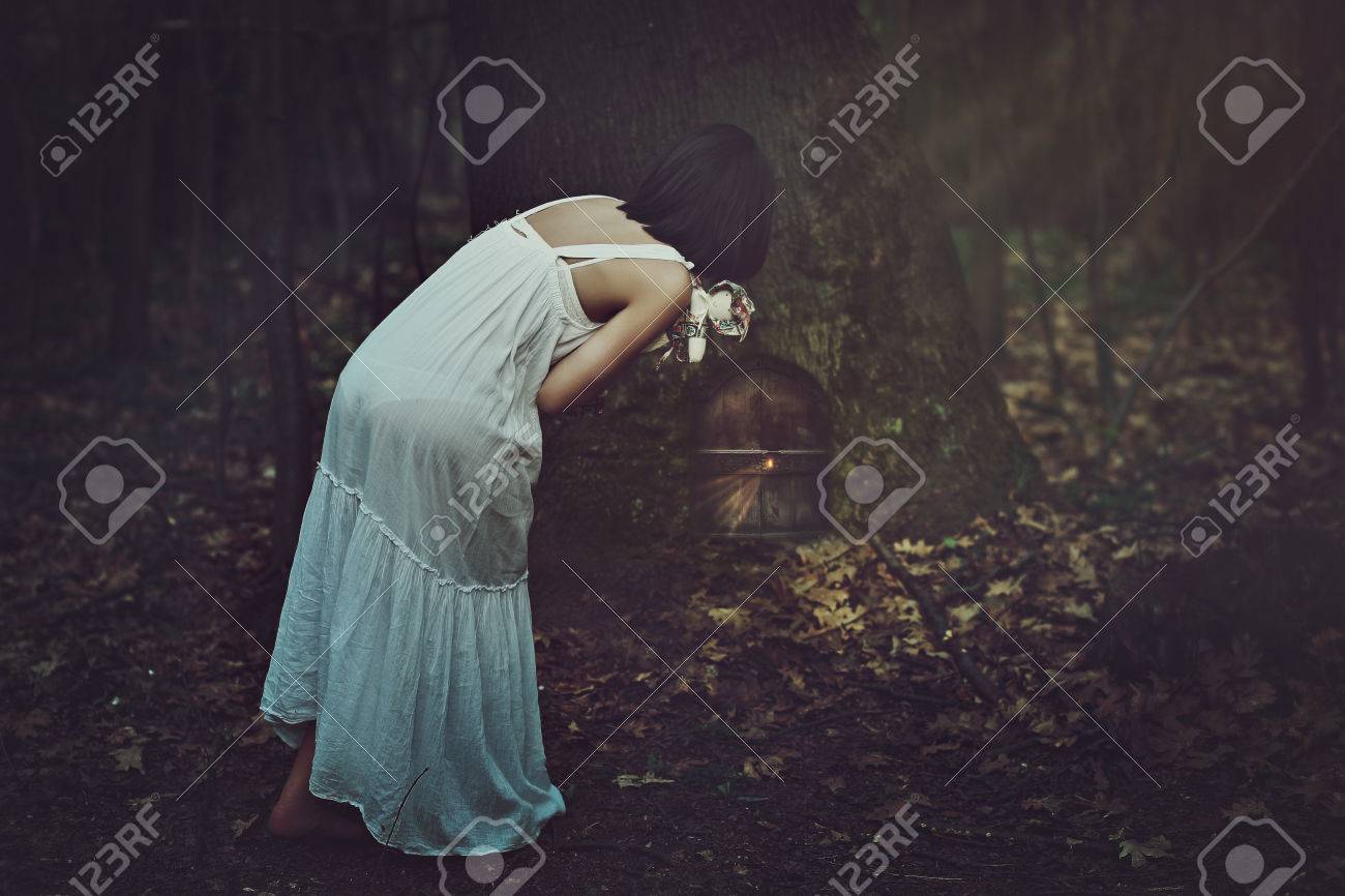 若い女性は 暗い森で奇妙な扉を見つけます ファンタジーと現実の概念 の写真素材 画像素材 Image