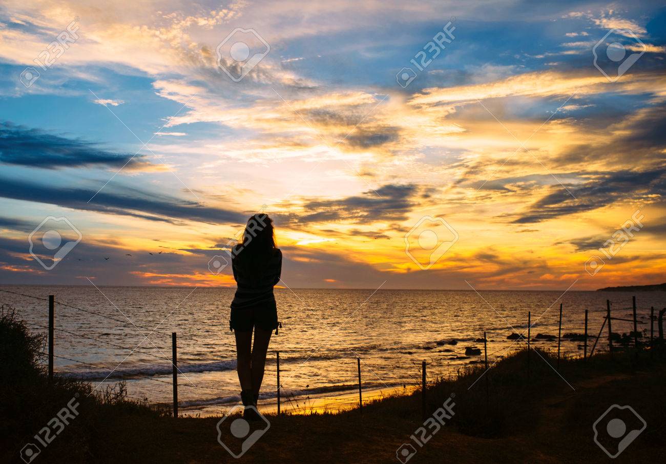 Silhouette of a Pensive Woman Standing at the Beach and Facing at the Peaceful Ocean During Sunset Time. - 44866494 Silhouette of a Pensive Woman Standing at the Beach and Facing at the Peaceful Ocean During Sunset Time. - 44866494