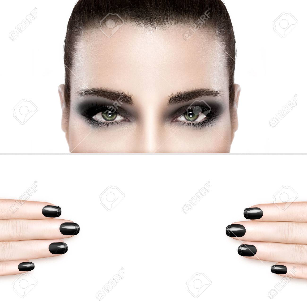 Dark smoky beauty and nail art concept with a woman wearing creative dark eye makeup holding a blank white card template covering her mouth with matching dark manicured nails. Portrait isolated on white with copy space for text. - 46755164 Dark smoky beauty and nail art concept with a woman wearing creative dark eye makeup holding a blank white card template covering her mouth with matching dark manicured nails. Portrait isolated on white with copy space for text. - 46755164