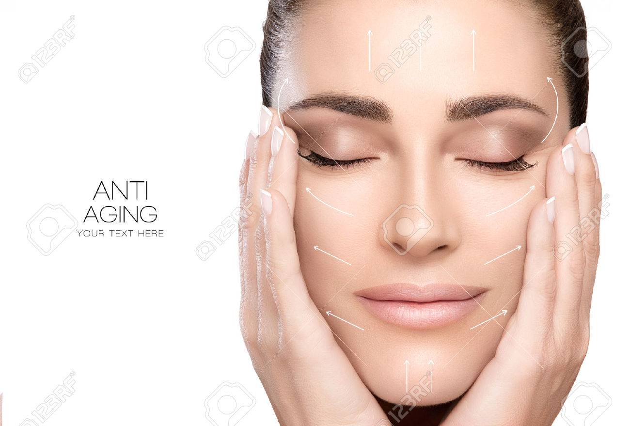 Anti aging treatment and plastic surgery concept. Beautiful young woman with hands on cheeks and eyes closed with a serene expression and white arrows over face. - 58030078 Anti aging treatment and plastic surgery concept. Beautiful young woman with hands on cheeks and eyes closed with a serene expression and white arrows over face. - 58030078