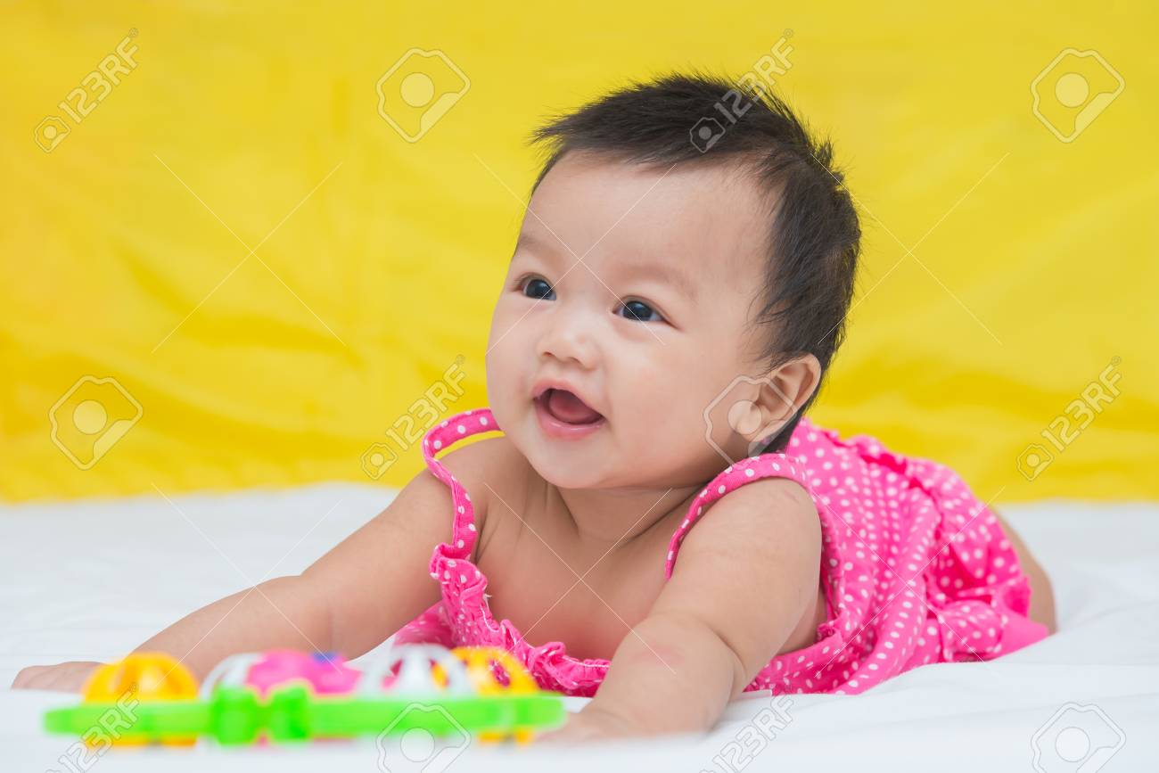 かわいい赤ちゃんグッズとベッドの上の微笑の女の子の肖像画 の写真素材 画像素材 Image