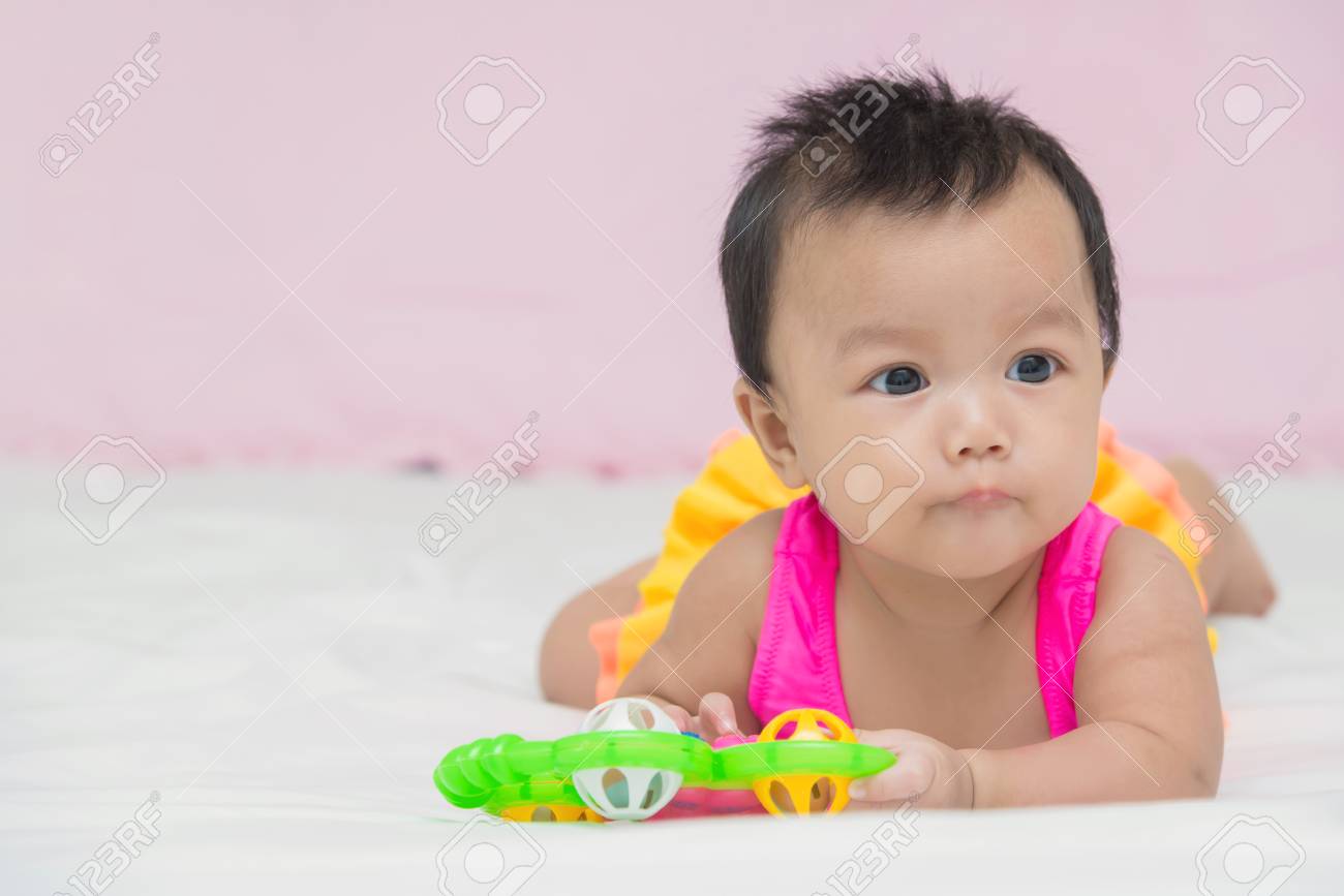 かわいい赤ちゃんグッズとベッドの上の微笑の女の子の肖像画 の写真