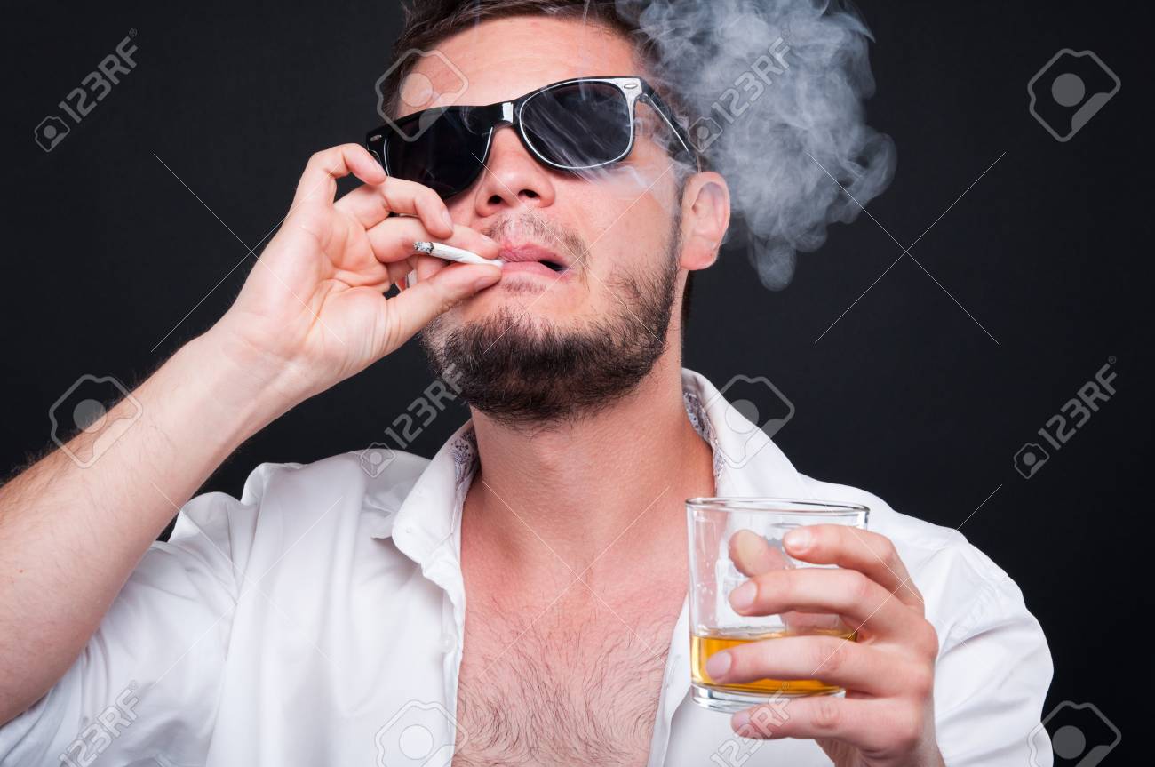 Closeu-up portrait of mafia killer smoking cigar and drinking alcohol on black background - 80505485 Closeu-up portrait of mafia killer smoking cigar and drinking alcohol on black background - 80505485