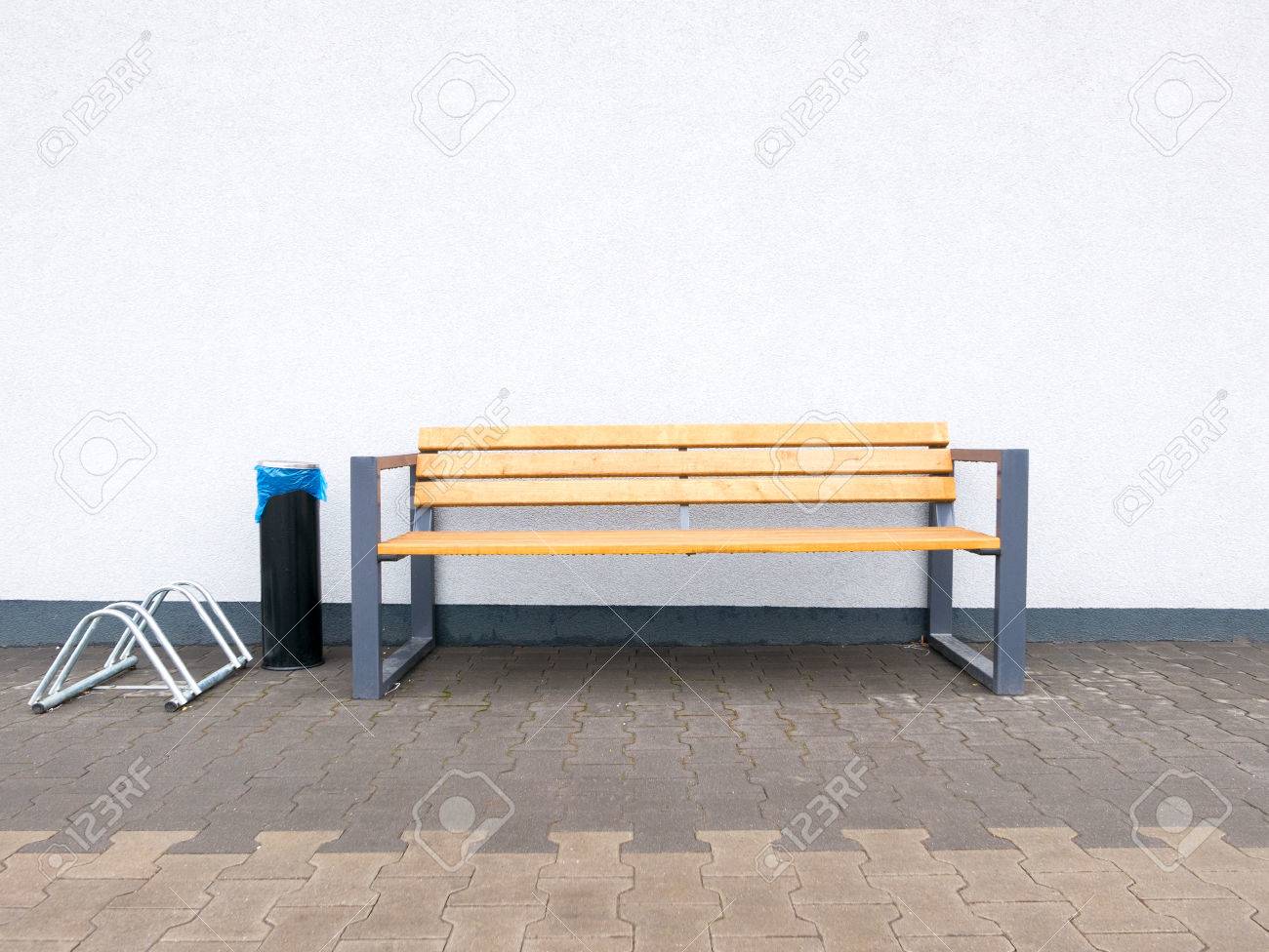 Empty modern outdoor bench and bike rack and industrial ashtray at wall background stock photo