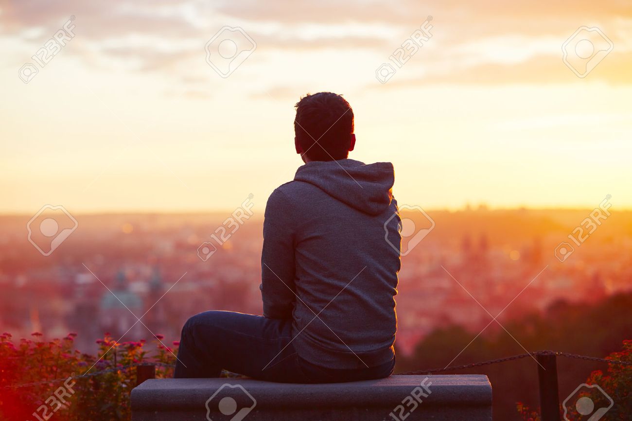 young man is looking at the sunrise stock photo picture and