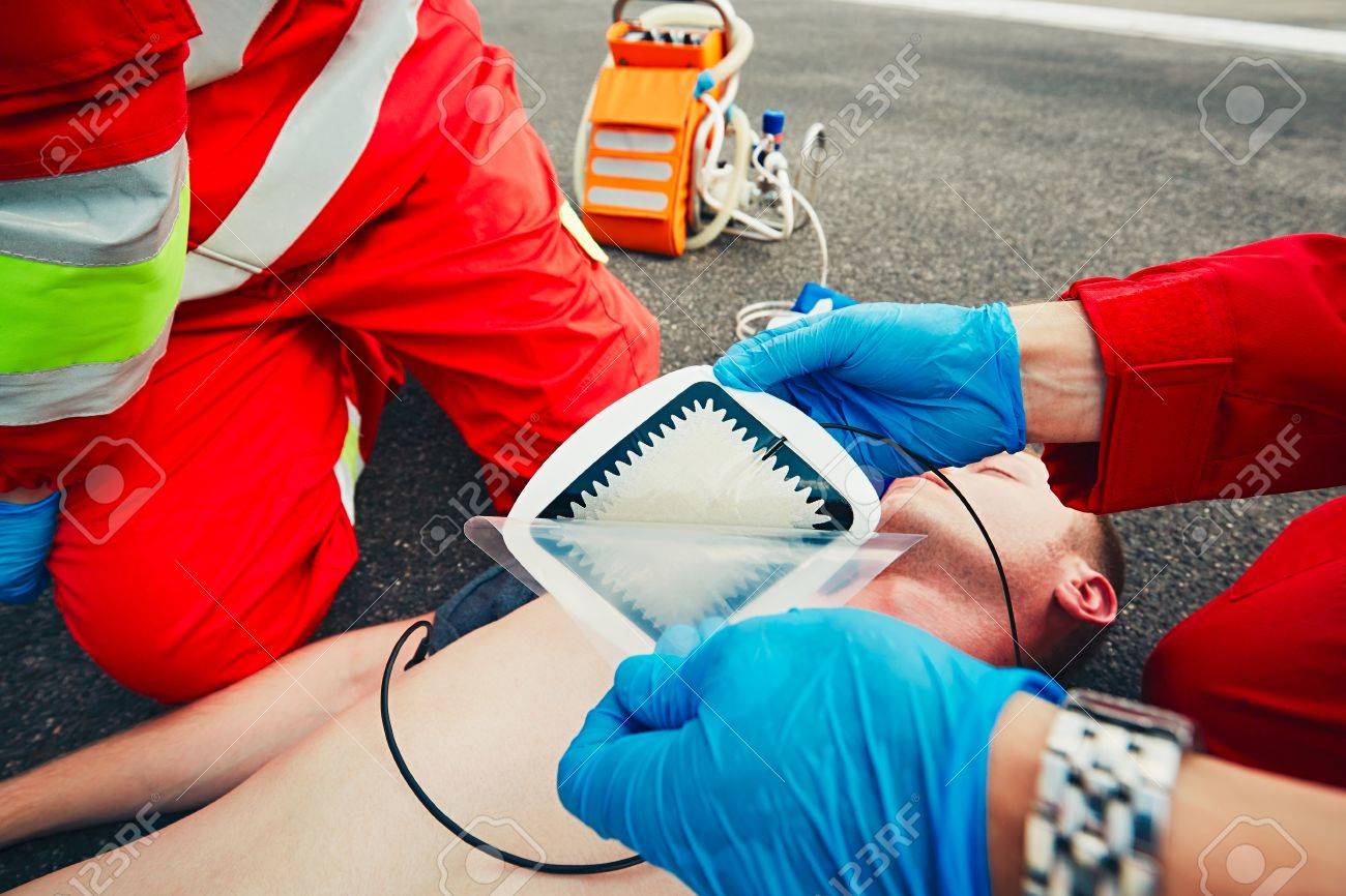 Electrodes of the defibrillator. Rescue team (doctor and a paramedic) resuscitating the man on the street. - 60418009 Electrodes of the defibrillator. Rescue team (doctor and a paramedic) resuscitating the man on the street. - 60418009