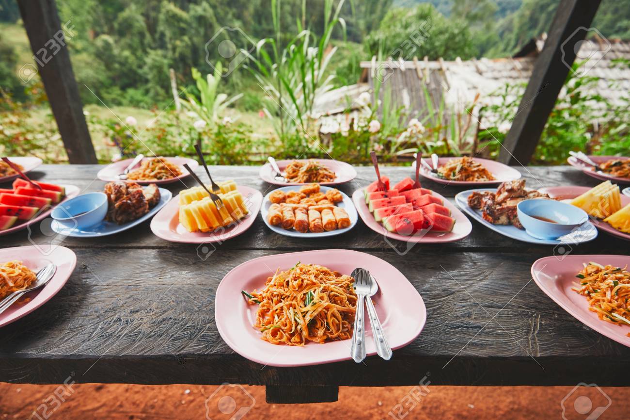 Lunch in the middle of the jungle. The table full of foods and fruits. Traditioal Pad Thai, spring rolls, melon and pineapple. Chiang Mai Province, Thailand. - 91700652 Lunch in the middle of the jungle. The table full of foods and fruits. Traditioal Pad Thai, spring rolls, melon and pineapple. Chiang Mai Province, Thailand. - 91700652