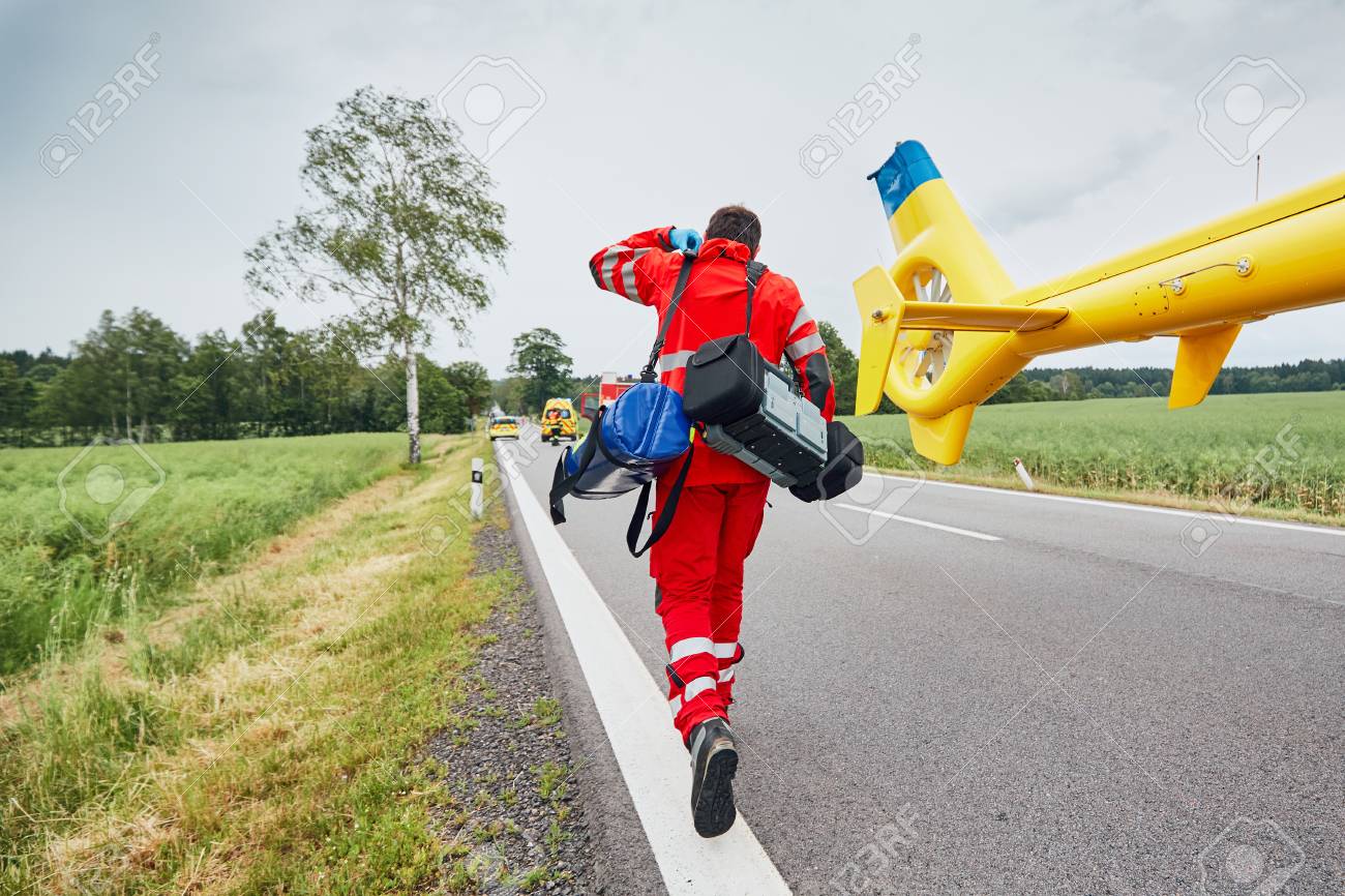 Doctor with defibrillator and other equipment running from helicopter. Teams of the Emergency medical service are responding to an traffic accident. - 92824289 Doctor with defibrillator and other equipment running from helicopter. Teams of the Emergency medical service are responding to an traffic accident. - 92824289