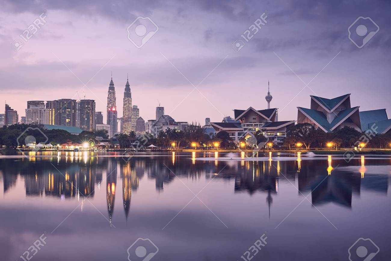 Moody sunrise in Kuala Lumpur in Malaysia. Reflection of the urban skyline in the lake. - 104683394 Moody sunrise in Kuala Lumpur in Malaysia. Reflection of the urban skyline in the lake. - 104683394