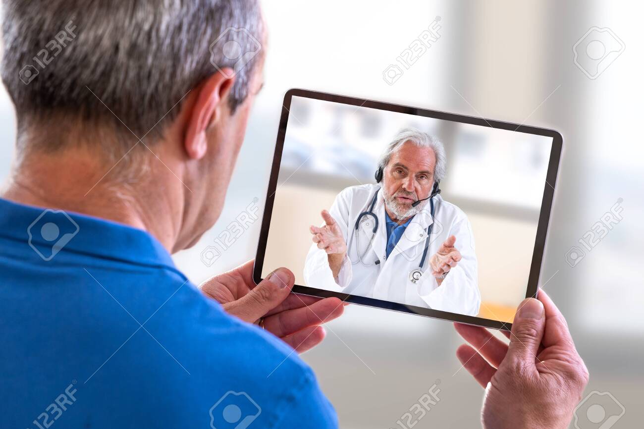 Telemedicine concept, Doctor sitting at hospital, with laptop, having an online call with a patient showing a ablet device - 127667145 Telemedicine concept, Doctor sitting at hospital, with laptop, having an online call with a patient showing a ablet device - 127667145