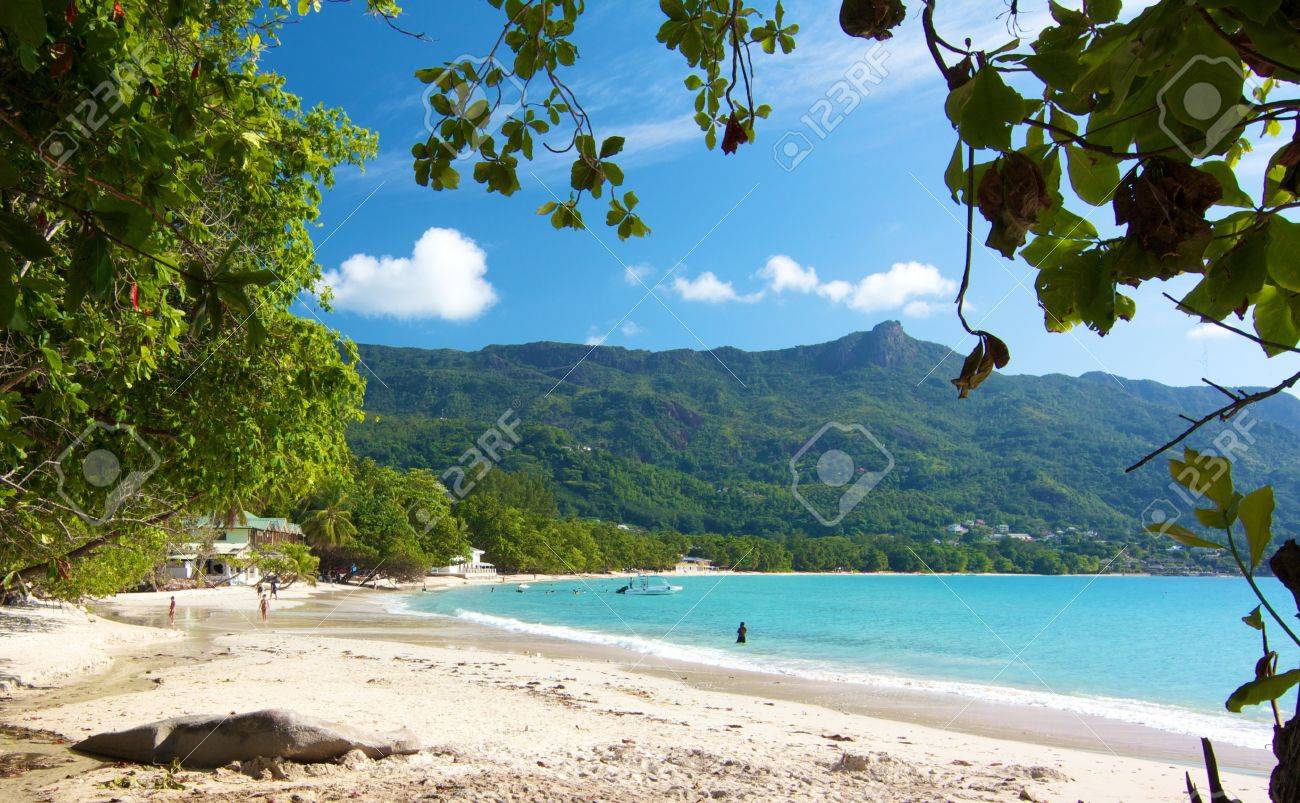 View over the amazing Beau Vallon bay with a few people walkingalong the white beach on Mahe island, Seychelles - 15450952 View over the amazing Beau Vallon bay with a few people walkingalong the white beach on Mahe island, Seychelles - 15450952