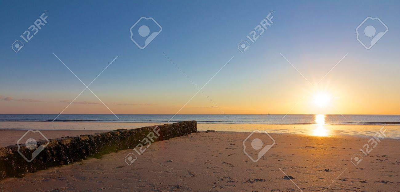 Rock groin leading towards a beautiful sunset on a lonely North Sea beach - 19903574 Rock groin leading towards a beautiful sunset on a lonely North Sea beach - 19903574