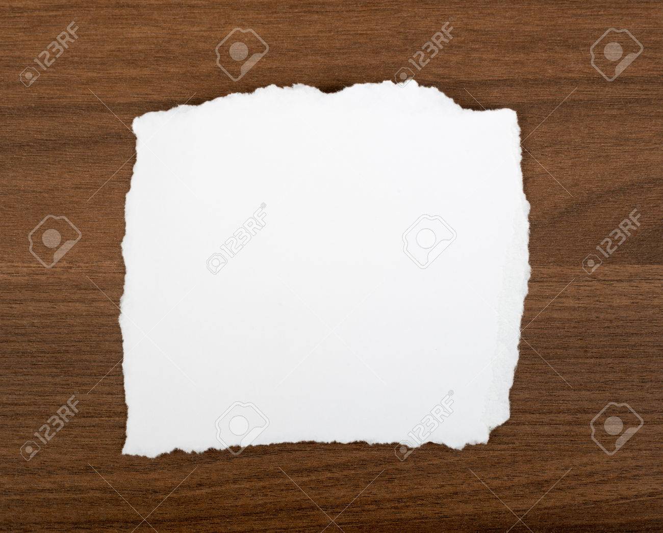 white blank piece of paper with uneven edges on brown wood table