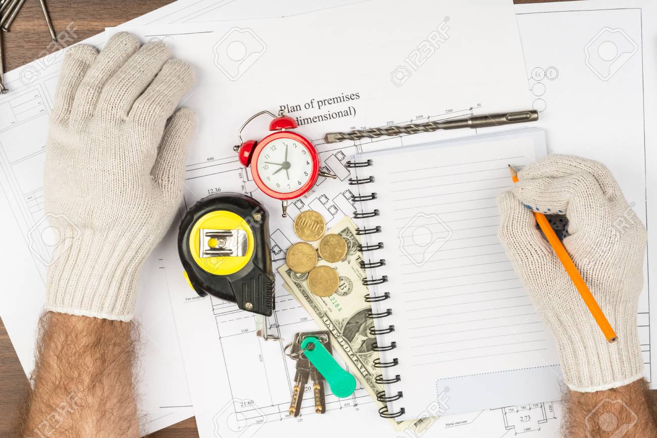 mans hands in gloves writing with alarm clock and drawings stock