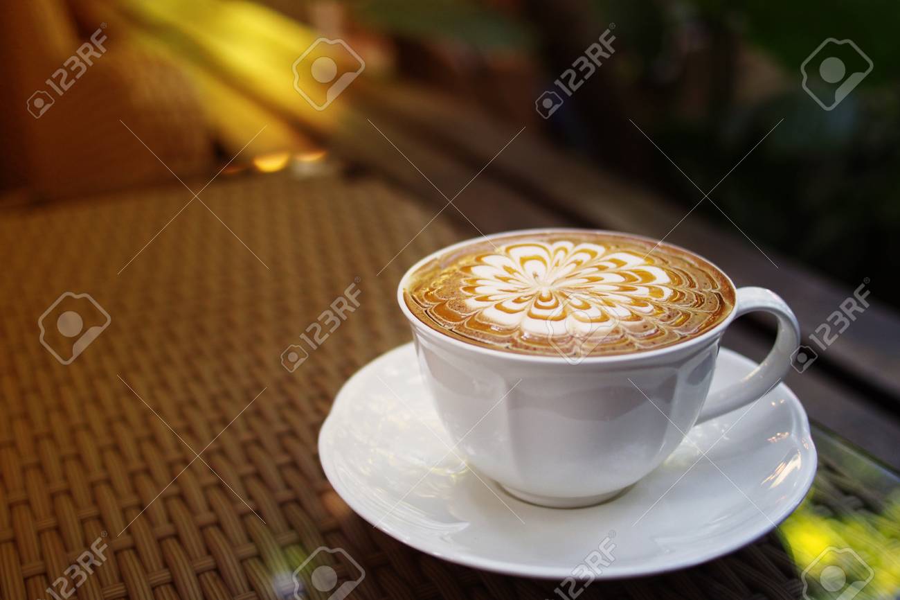 Hot Coffee Caramel Macchiato Cappuccino Cup On Garden Woven Table Background With Warm Morning Sunlight Hot Coffee Caramel Macchiato Cappuccino Cup On Garden Woven Table Background With Warm Morning Sunlight