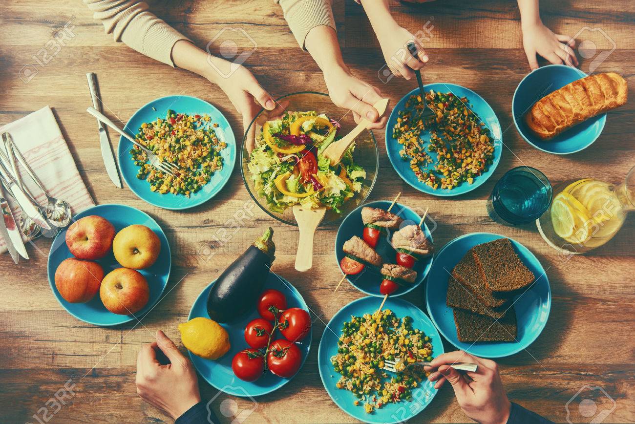 Top view of family having dinner together sitting at the rustic wooden table. Enjoying family dinner together. - 52154689 Top view of family having dinner together sitting at the rustic wooden table. Enjoying family dinner together. - 52154689