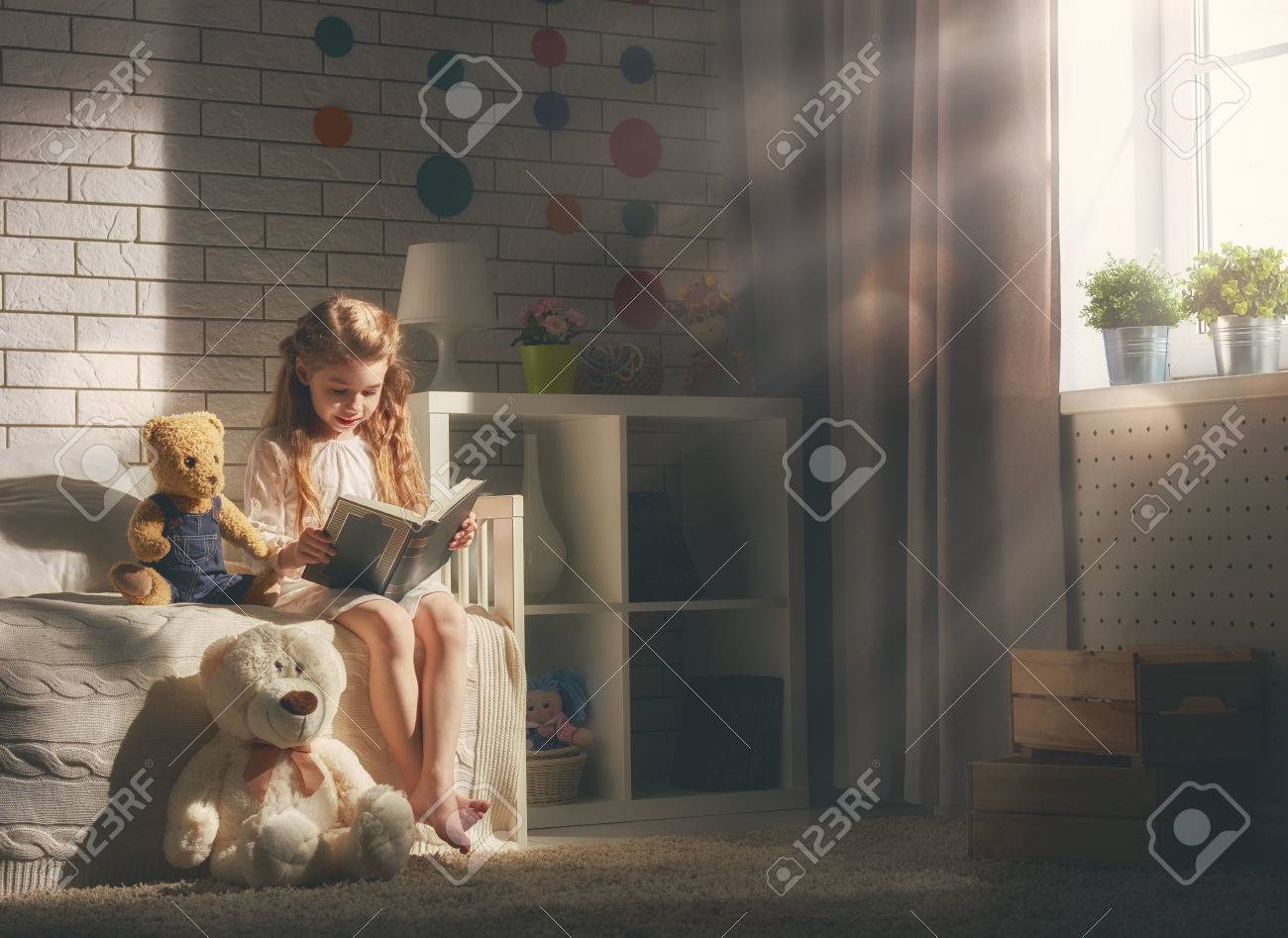 Cute little child girl reading a book. Kid girl sitting in her bed. - 56780888 Cute little child girl reading a book. Kid girl sitting in her bed. - 56780888