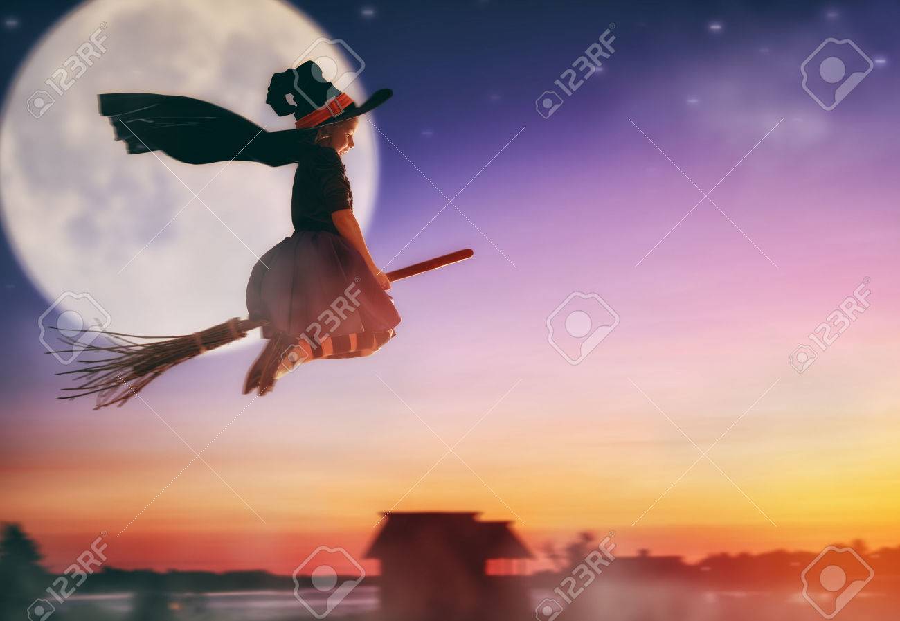 Happy Halloween! Cute little witch flying on a broomstick. Beautiful young child girl in witch costume outdoors. - 62992008 Happy Halloween! Cute little witch flying on a broomstick. Beautiful young child girl in witch costume outdoors. - 62992008