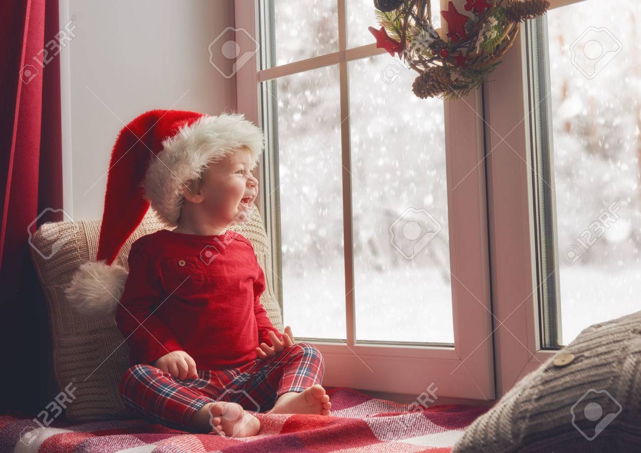 Joyeux Noel Et Bonnes Fetes Mignon Petit Bebe Fille Assise Pres De La Fenetre Et En Regardant La Foret D Hiver Chambre Decoree A Noel Kid Beneficie De La Chute De Neige Banque