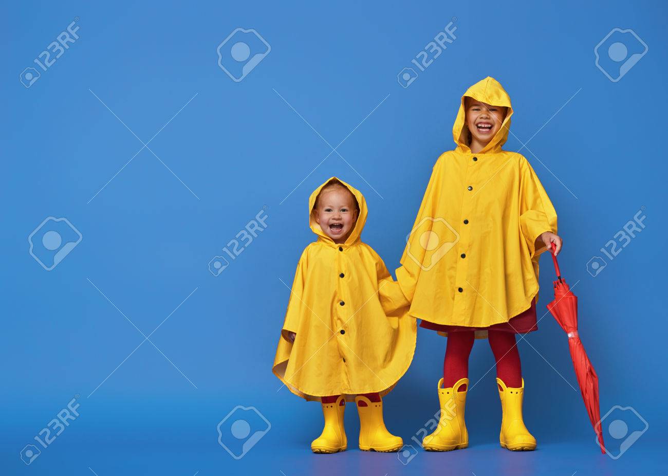 Zwei Gluckliche Lustige Kinder Mit Roten Regenschirm Posiert Auf Blauen Wand Hintergrund Madchen Tragt Einen Gelben Regenmantel Und Gummistiefel Lizenzfreie Fotos Bilder Und Stock Fotografie Image 84289474