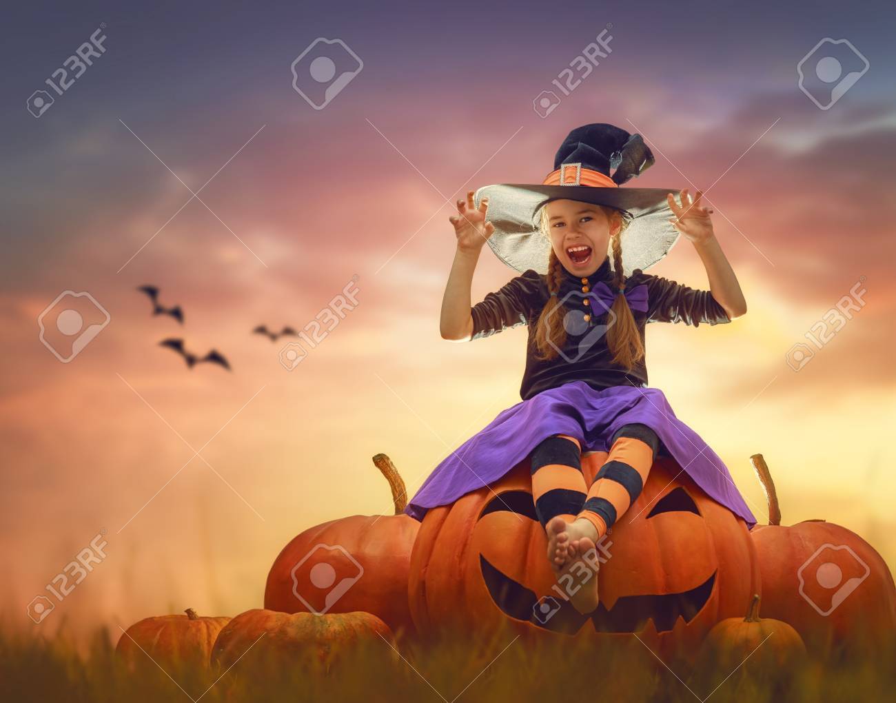 Happy Halloween! Cute little witch with pumpkins. Beautiful young child girl in costume outdoors. - 87597341 Happy Halloween! Cute little witch with pumpkins. Beautiful young child girl in costume outdoors. - 87597341