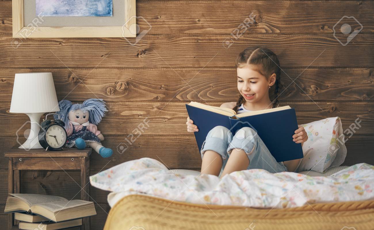 かわいい女の子は 自宅の部屋のベッドで本を読んでいます の写真素材 画像素材 Image