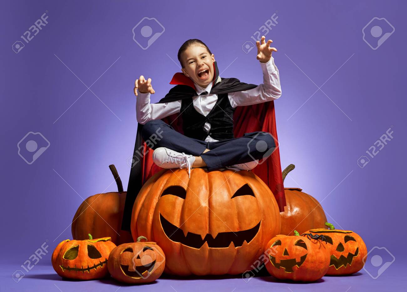 Happy Halloween! Cute little Dracula with a pumpkin on purple - 129603333 Happy Halloween! Cute little Dracula with a pumpkin on purple - 129603333