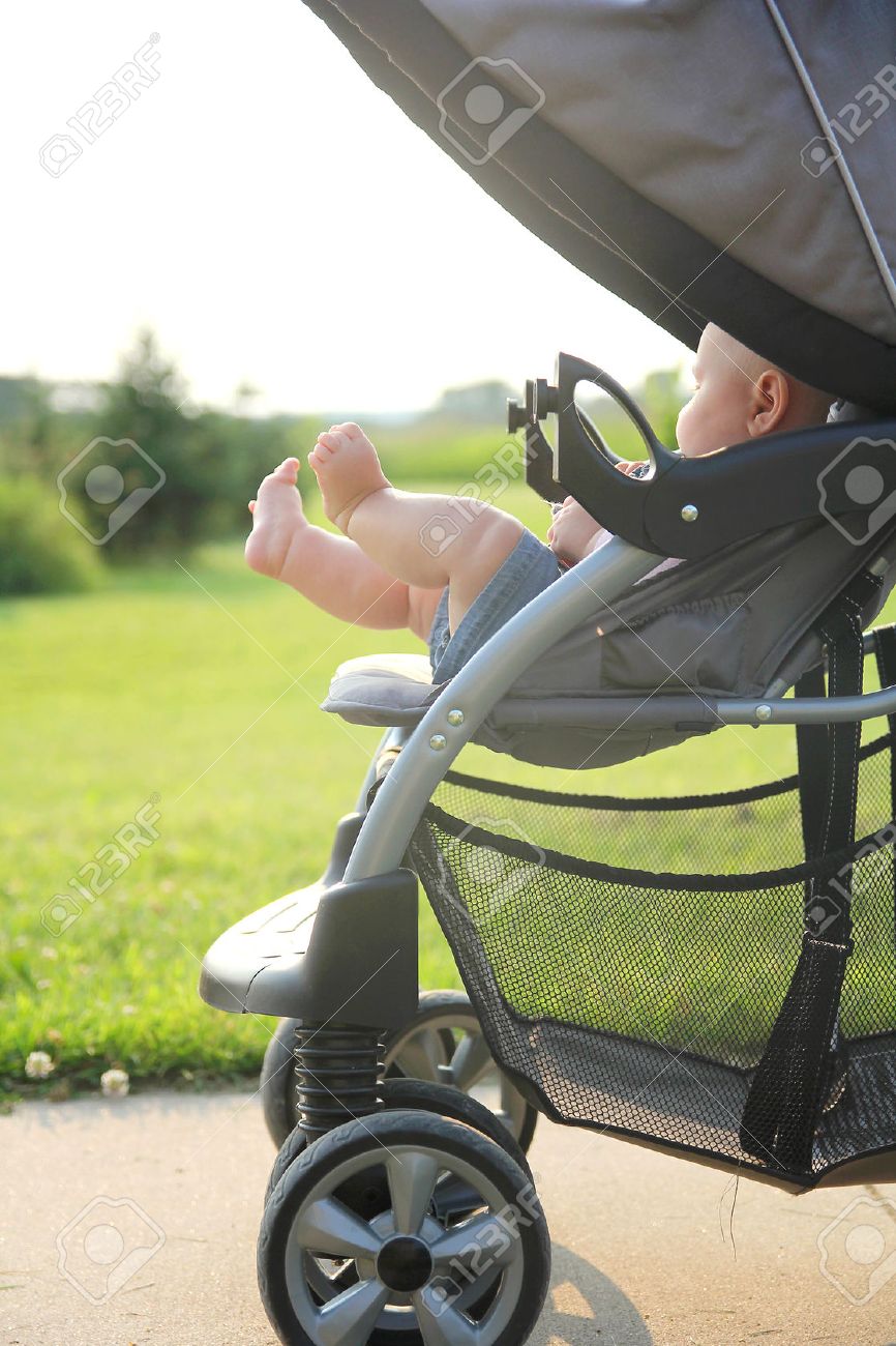 The cute, chubby legs of a newborn baby girl are sticking out of a stroller while on a walk outside in the country. - 43154018 The cute, chubby legs of a newborn baby girl are sticking out of a stroller while on a walk outside in the country. - 43154018