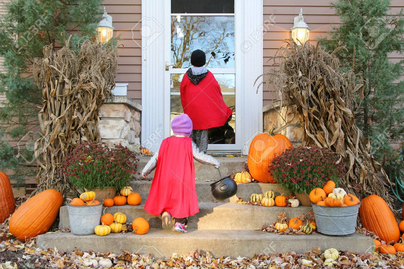Two young children dressed up in costumes are waiting at a house for candy while Trick-or-Treating on Halloween. - 45092551 Two young children dressed up in costumes are waiting at a house for candy while Trick-or-Treating on Halloween. - 45092551