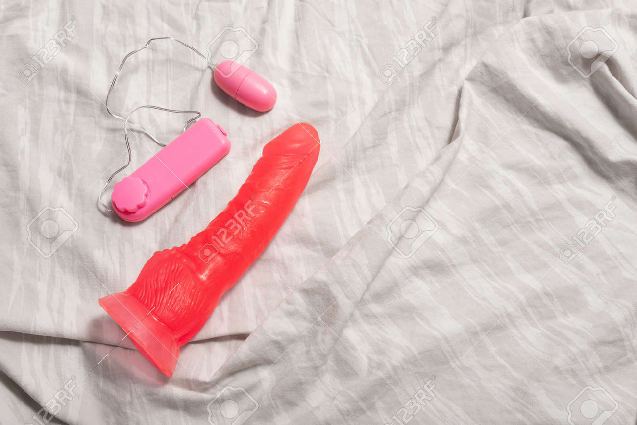 Dildo, Penis Toy For Woman, Battery Operated Pink On Bed Sheets Stock Photo, Picture And Royalty Free Image