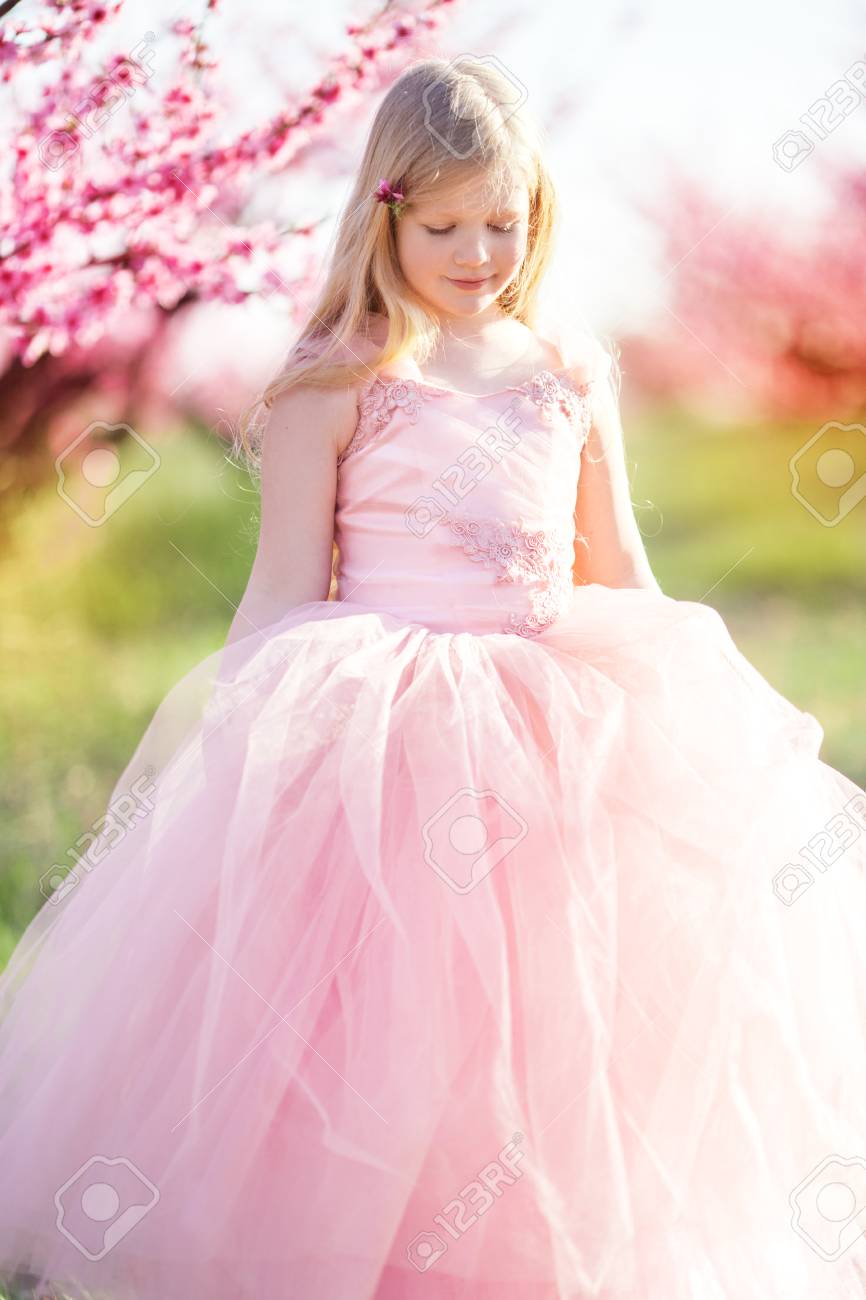 幸せな少女は ピンクの花の咲く桃畑で楽しいファッション ピンク ドレスを着ています の写真素材 画像素材 Image