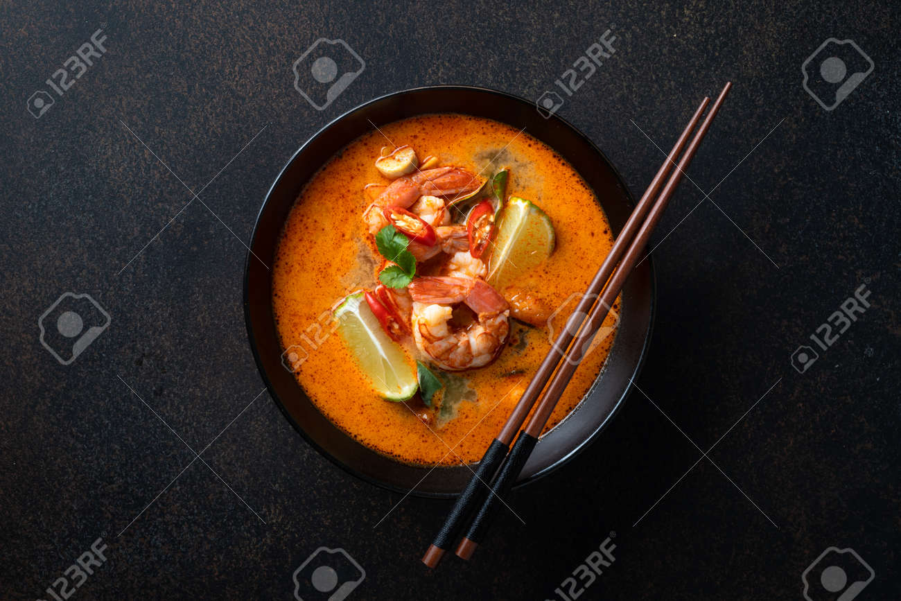 Tom Yum soup with shrimp in a ceramic black bowl with chopsticks on a dark background, top view - 169788399 Tom Yum soup with shrimp in a ceramic black bowl with chopsticks on a dark background, top view - 169788399