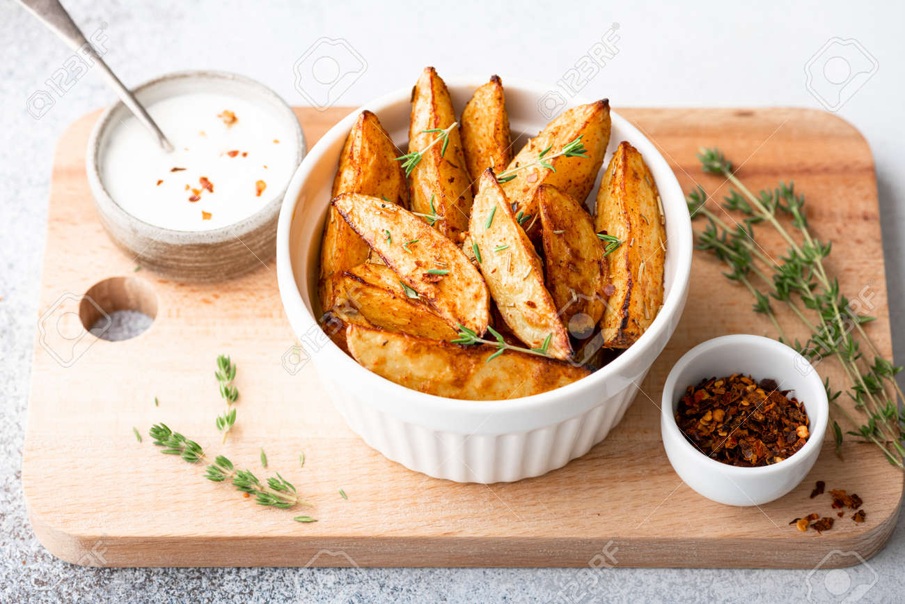 baked potato wedges with sauce on a light background - 169788402 baked potato wedges with sauce on a light background - 169788402