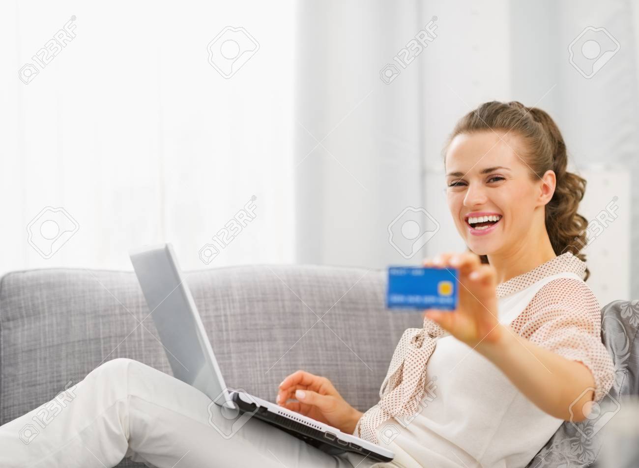 happy young housewife with laptop showing credit card stock photo