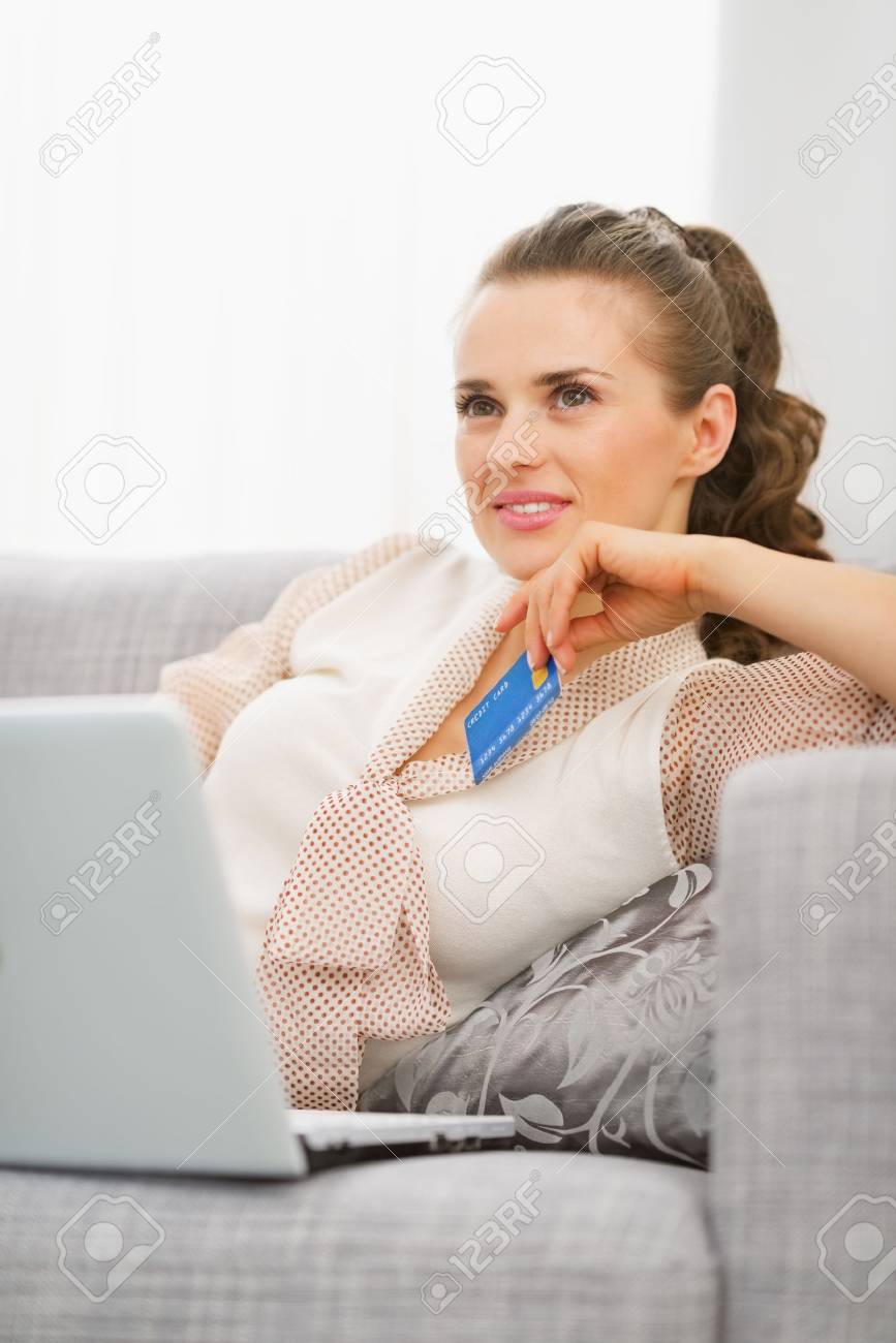 thoughtful young housewife with laptop and credit card stock photo