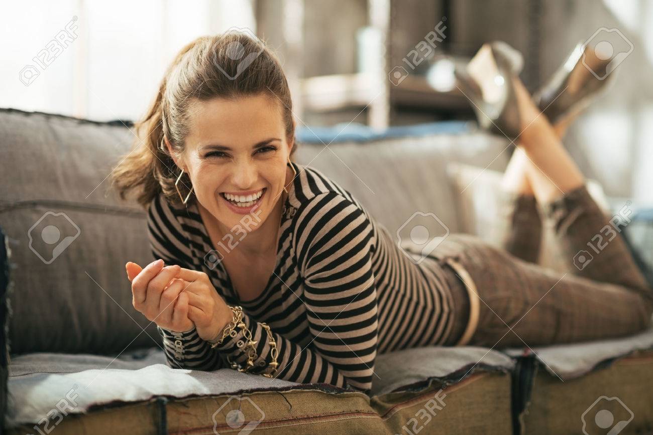 Portrait of smiling young woman laying on divan in loft apartment - 40310539 Portrait of smiling young woman laying on divan in loft apartment - 40310539