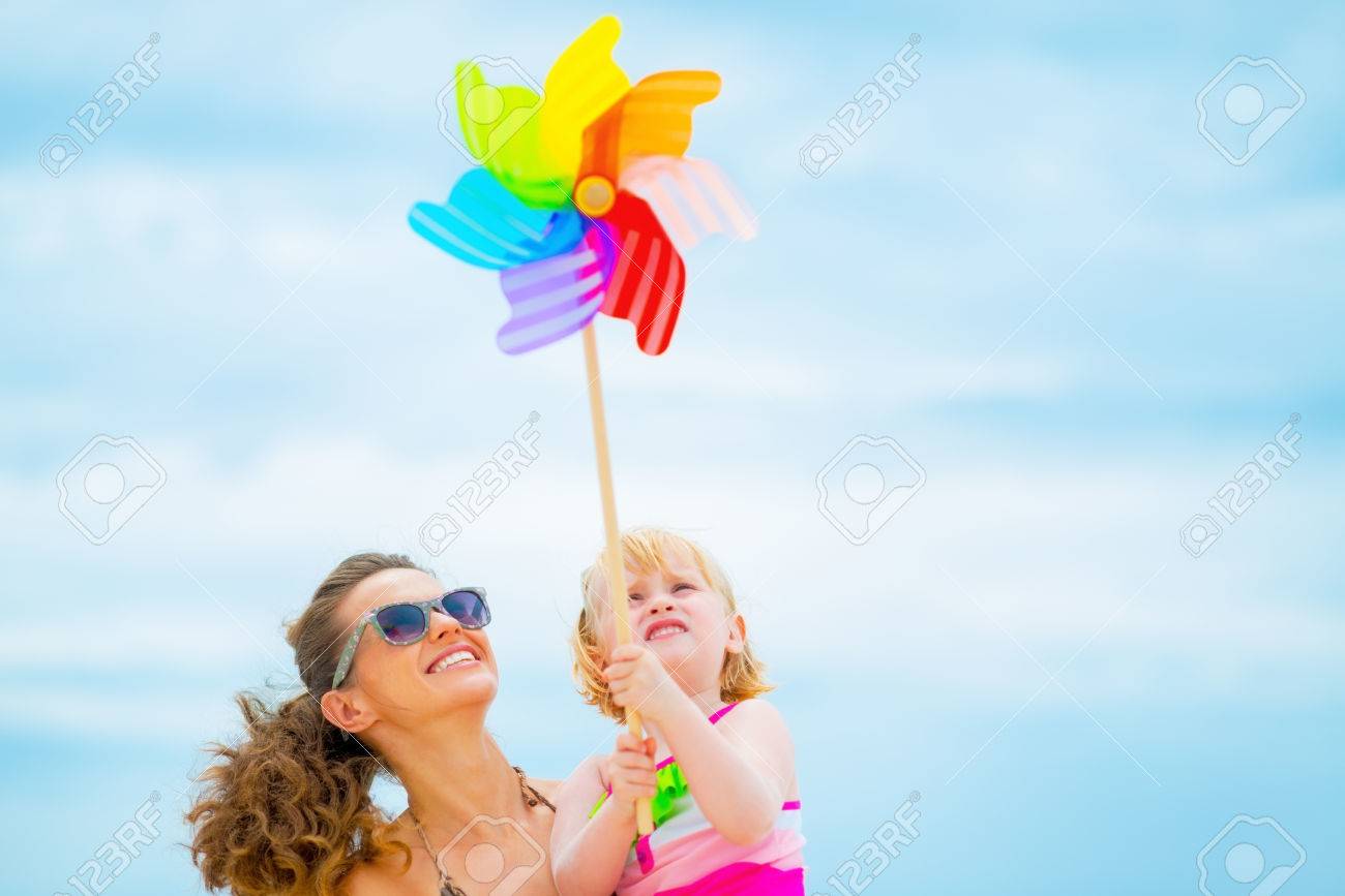Happy mother and baby girl holding colorful windmill toy - 31329355 Happy mother and baby girl holding colorful windmill toy - 31329355