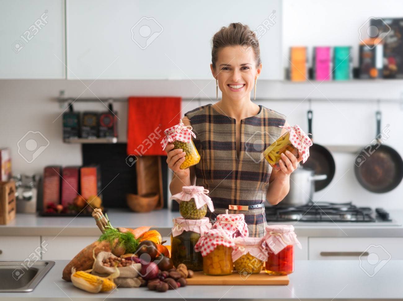 Holding up two jars of preserved vegetables, this happy, elegant woman is proud of all she has accomplished in preserving fresh vegetables. How tasty the winter months will be... - 46569345 Holding up two jars of preserved vegetables, this happy, elegant woman is proud of all she has accomplished in preserving fresh vegetables. How tasty the winter months will be... - 46569345
