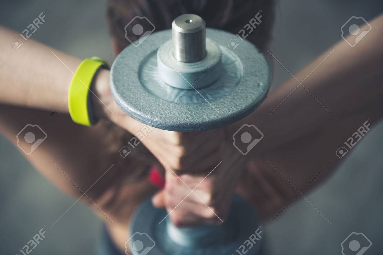 Body and mind workout in loft fitness studio. Fitness woman holding dumbbell behind head. Close up - 52593202 Body and mind workout in loft fitness studio. Fitness woman holding dumbbell behind head. Close up - 52593202