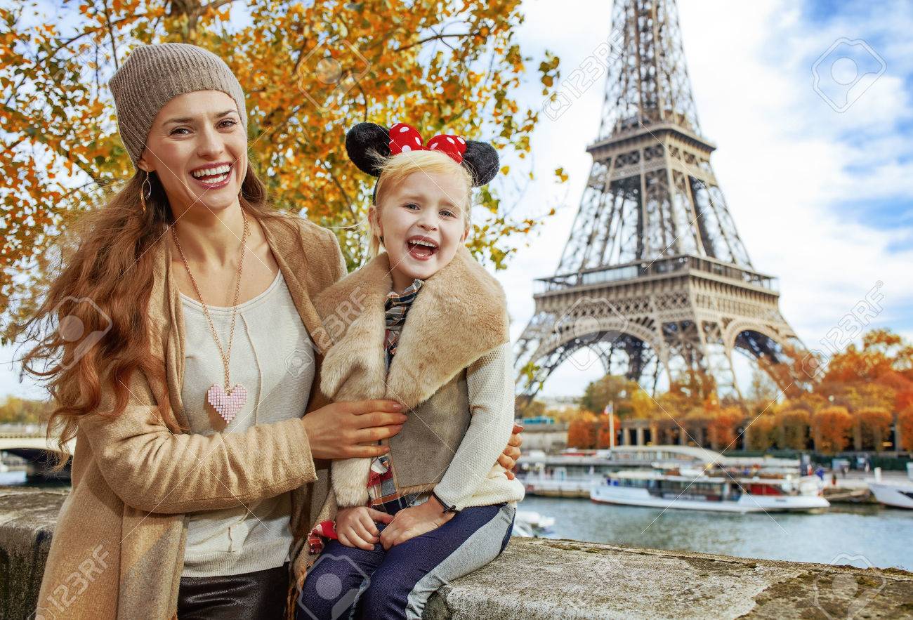 Perfect autumn holidays in Disneyland and Paris. Portrait of smiling tourists mother and daughter in Minnie Mouse Ears on embankment near Eiffel tower in Paris, France sitting on the parapet - 85273175 Perfect autumn holidays in Disneyland and Paris. Portrait of smiling tourists mother and daughter in Minnie Mouse Ears on embankment near Eiffel tower in Paris, France sitting on the parapet - 85273175