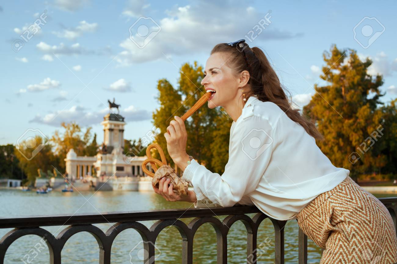 happy modern tourist woman in white blouse and shorts in Madrid, Spain eating traditional Spain churro. churros - classic Madrid sweet snack. woman travel alone. perfect destination choice.solo travel - 115932246 happy modern tourist woman in white blouse and shorts in Madrid, Spain eating traditional Spain churro. churros - classic Madrid sweet snack. woman travel alone. perfect destination choice.solo travel - 115932246