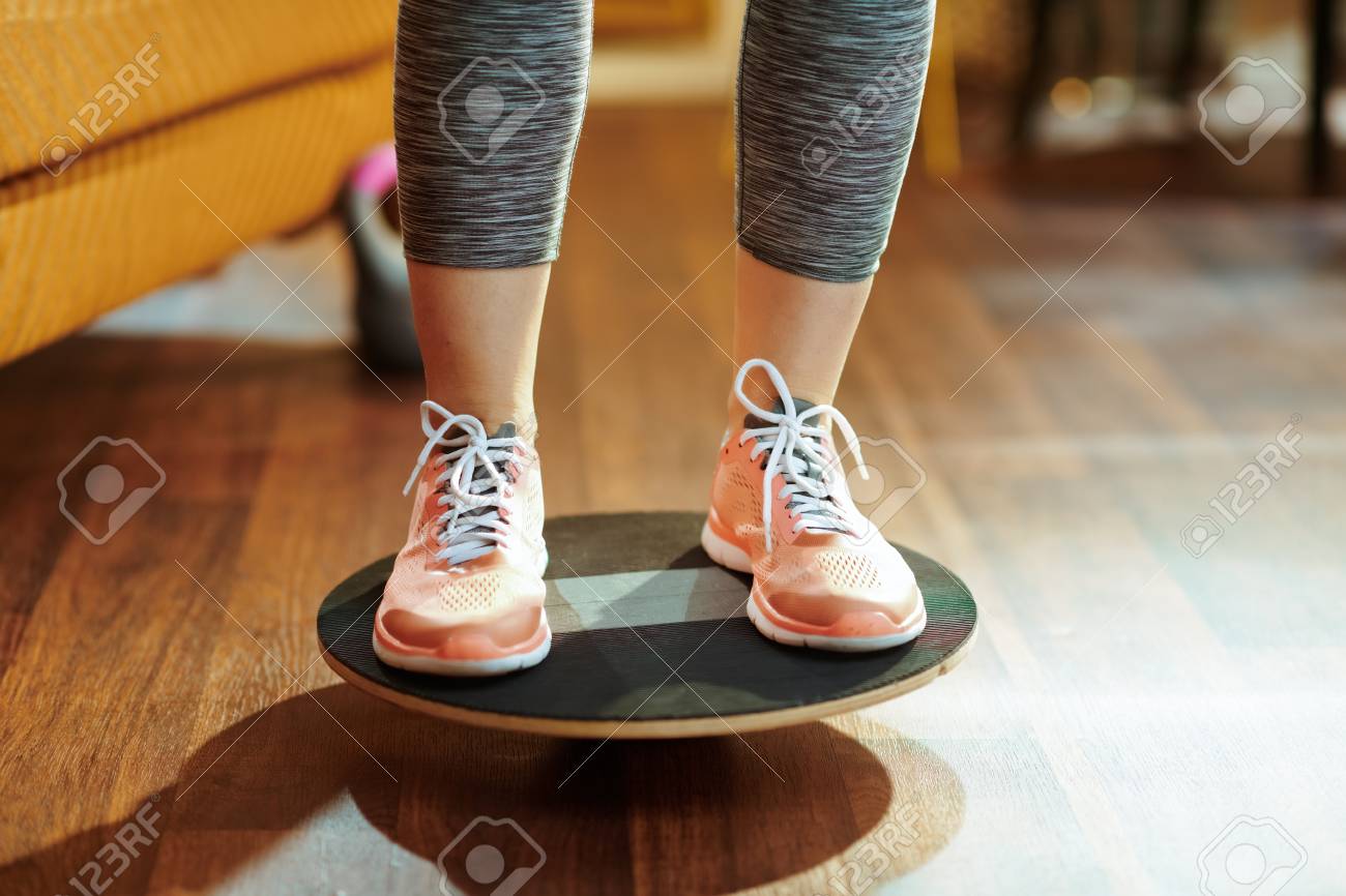 Closeup on fit sports woman in fitness clothes at modern home while training using balance board. - 122822178 Closeup on fit sports woman in fitness clothes at modern home while training using balance board. - 122822178