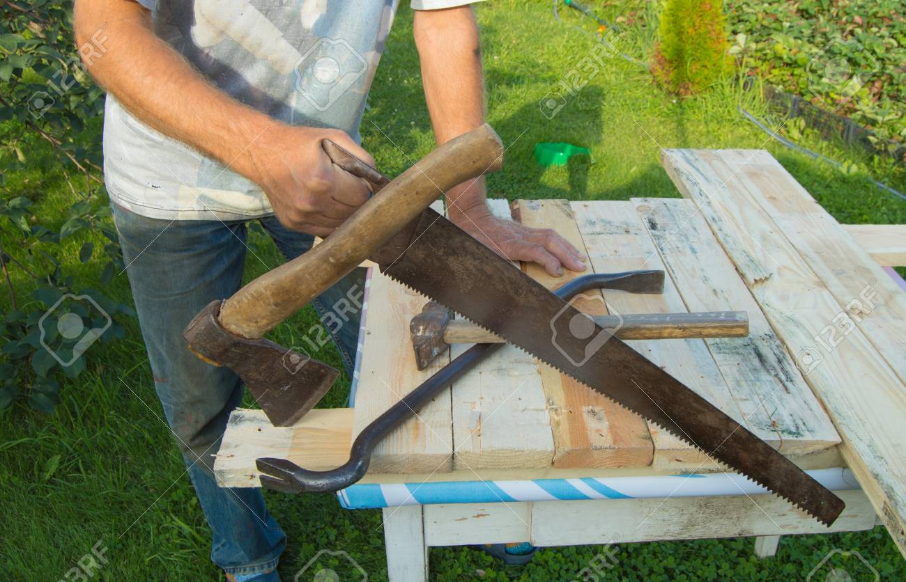 man uses a hacksaw a hatchet a claw hammer for construction