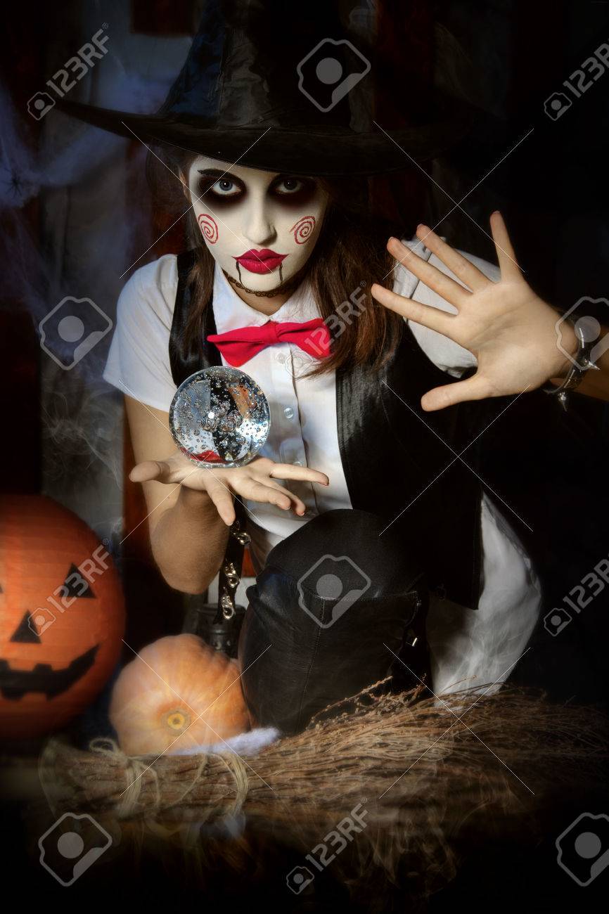 Halloween, Le Mysticisme, La Magie, Le Mystère. Maquillage Dans Le Style De  Billy Poupée. Fille Sorcière Tenant Une Boule Magique Transparente Et Jette  Un Sort Sur Lui. Banque D'images Et Photos Libres