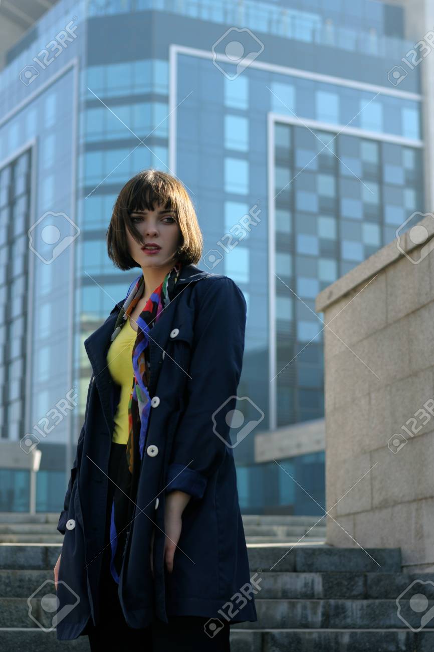 都市の背景にフォーマルな服でビジネスの女性 彼女は茶色の髪とボブの髪型 彼女の首に青いレインコートとスカーフを着ています の写真素材 画像素材 Image
