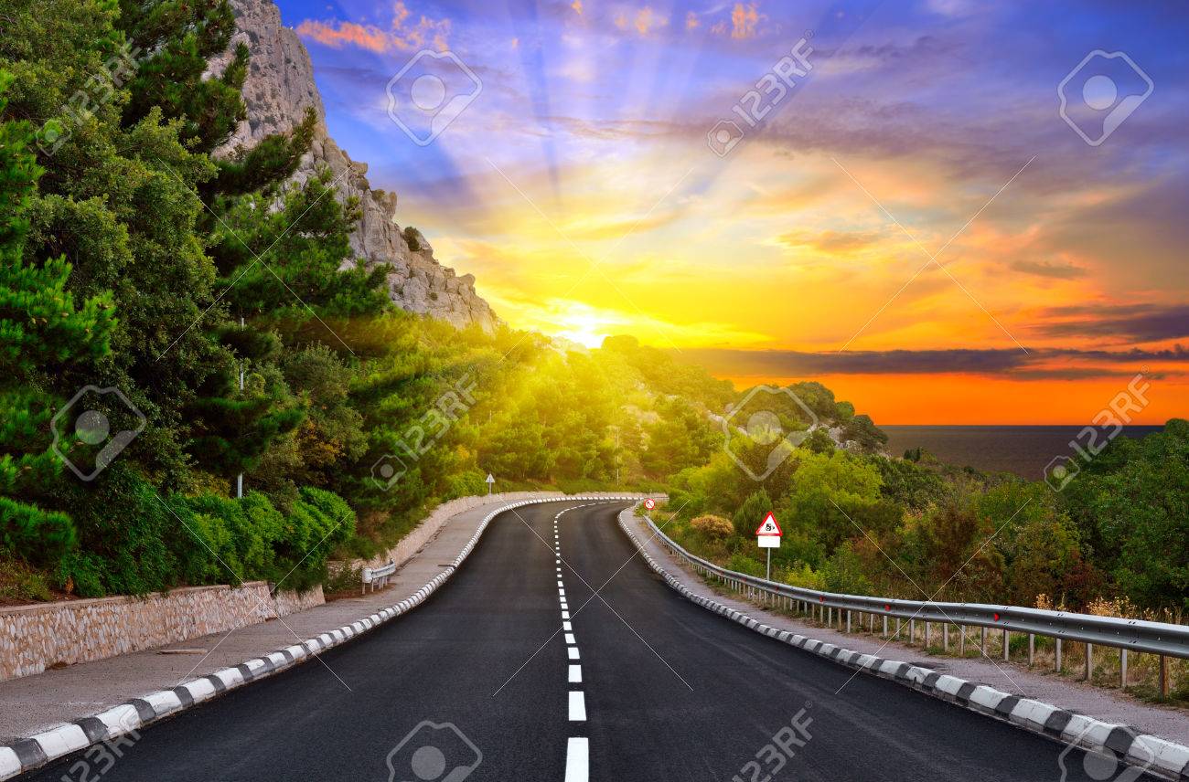 Highway against mountains and a dramatic sunset - 27724828 Highway against mountains and a dramatic sunset - 27724828