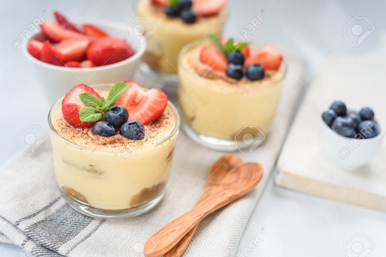 Homemade tiramisu, traditional Italian dessert in glass on white wooden table - 101228671 Homemade tiramisu, traditional Italian dessert in glass on white wooden table - 101228671