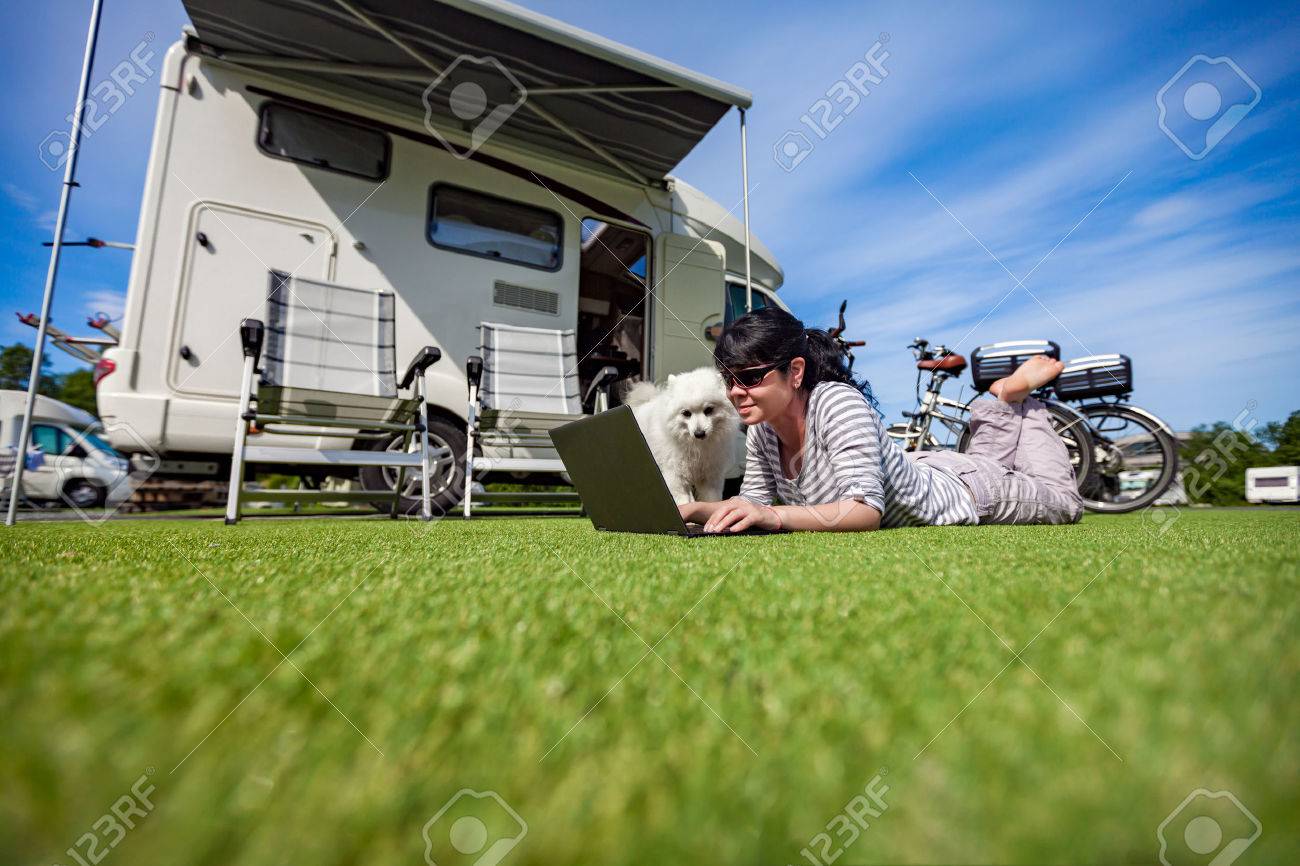 Woman on the grass with a dog looking at a laptop. Caravan car Vacation. Family vacation travel, holiday trip in motorhome - 62009824 Woman on the grass with a dog looking at a laptop. Caravan car Vacation. Family vacation travel, holiday trip in motorhome - 62009824