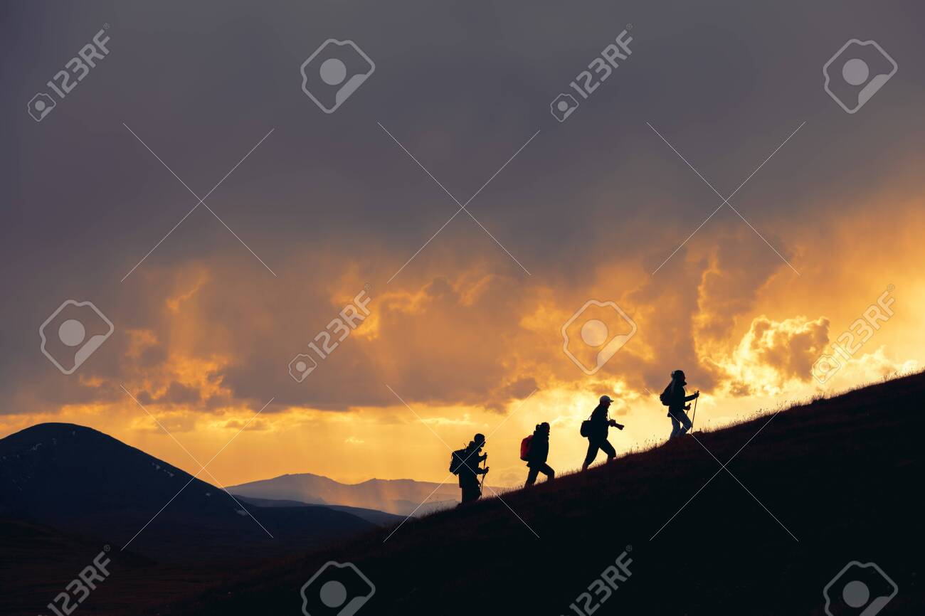 Group of unrecognizable hikers are walking at majestic sunset in mountains - 146037935 Group of unrecognizable hikers are walking at majestic sunset in mountains - 146037935
