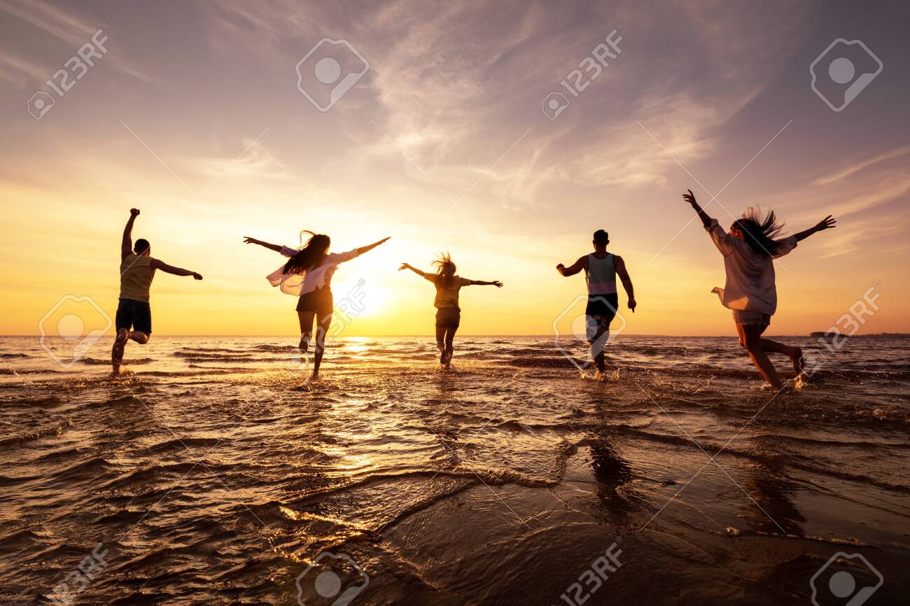 Five happy friends runs with raised arms at sunset beach - 146895621 Five happy friends runs with raised arms at sunset beach - 146895621